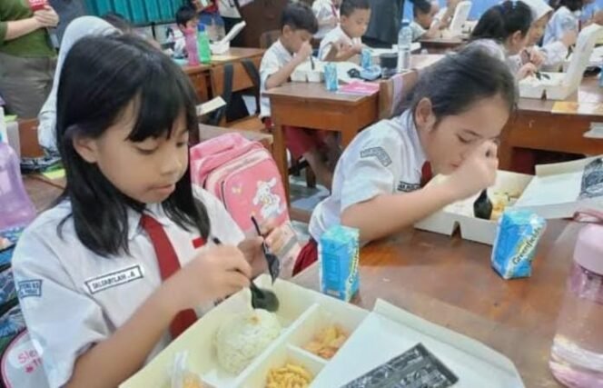 
					POTO : Siswi sekolah dasar menikmati makan bergizi gratis (Antara)